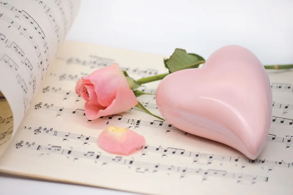 楽譜の上にピンクのバラとピンクのハートが乗っている